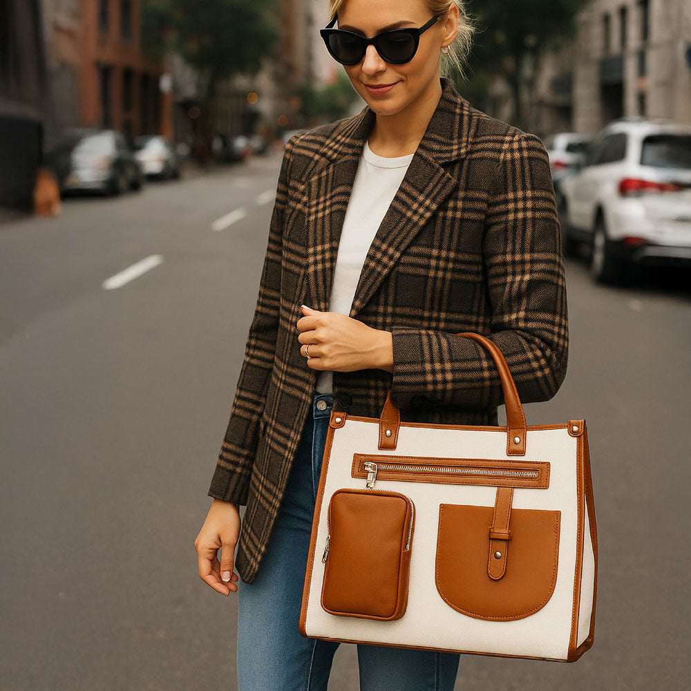 Woman standing outside wearing a plaid blazer and holding a canvas tote on her arm.