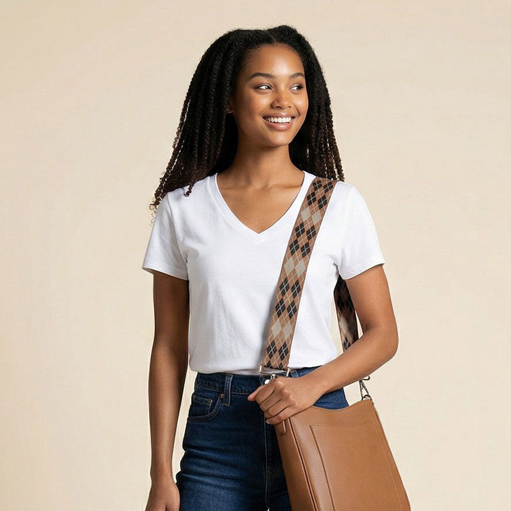 Woman wearing a camel leather bag with a argyle patterned bag strap against a beige background