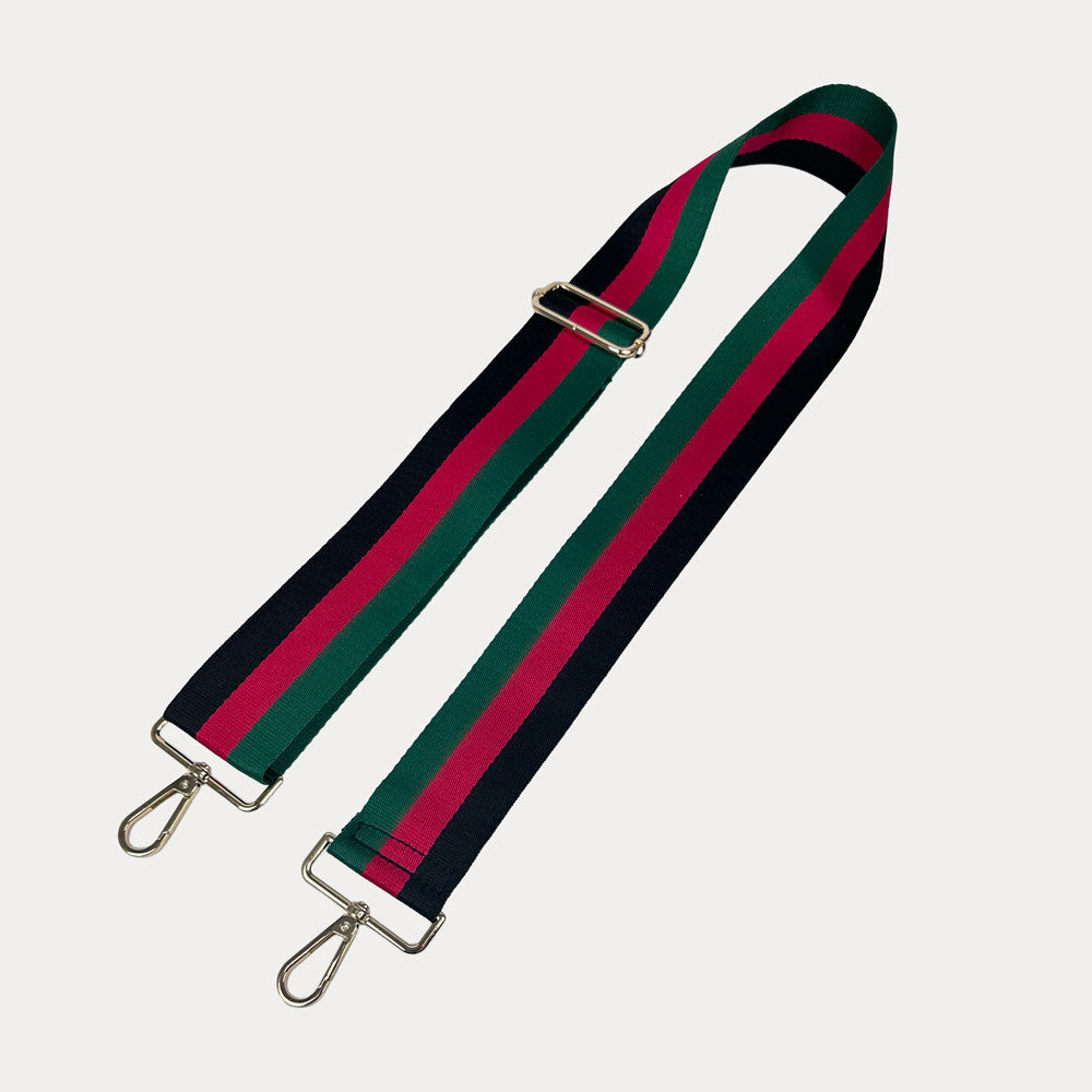 Black, red, and green striped bag strap with gold hardware on a light gray background,