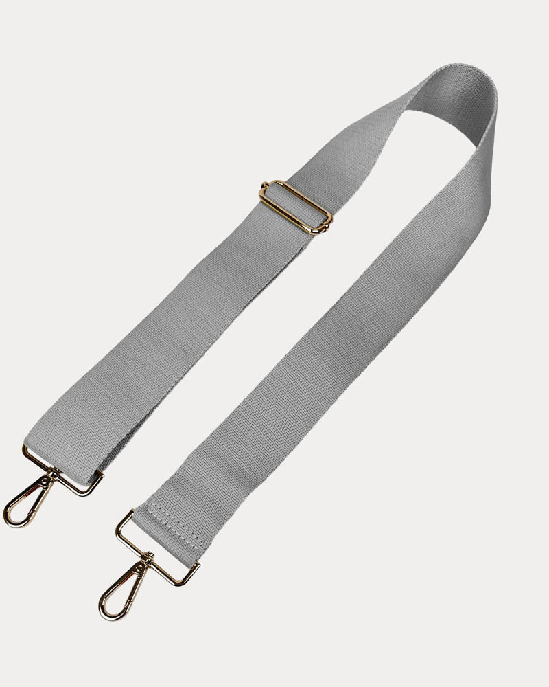 Gray bag strap with gold hardware on a light gray background