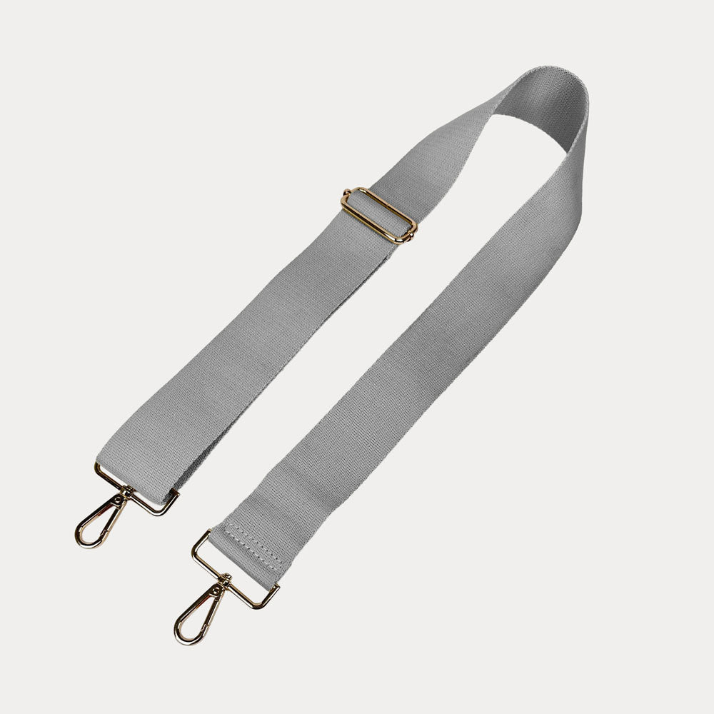 Gray bag strap with gold hardware on a light gray background