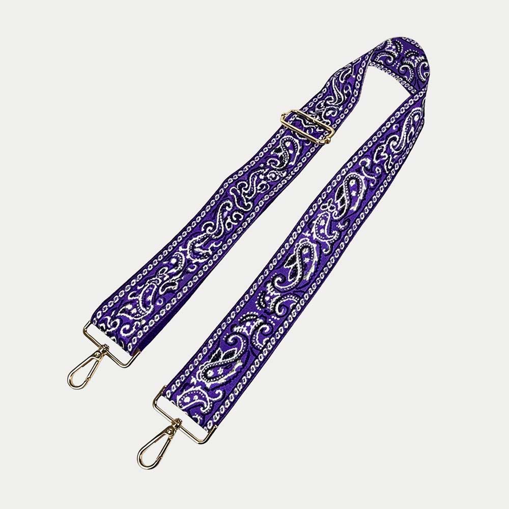 Purple paisley patterned strap with gold hardware on a light gray background