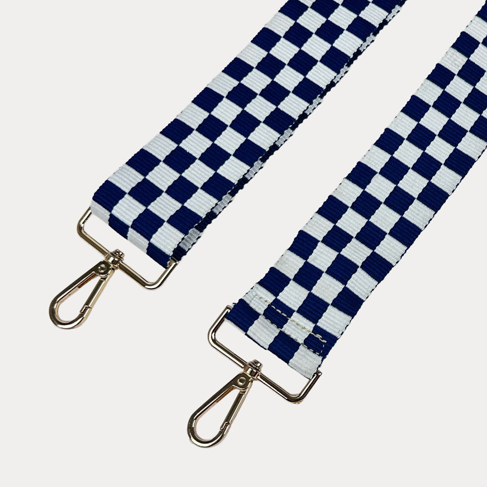 Navy and white checkered bag strap with gold metal clasp trim on a white background