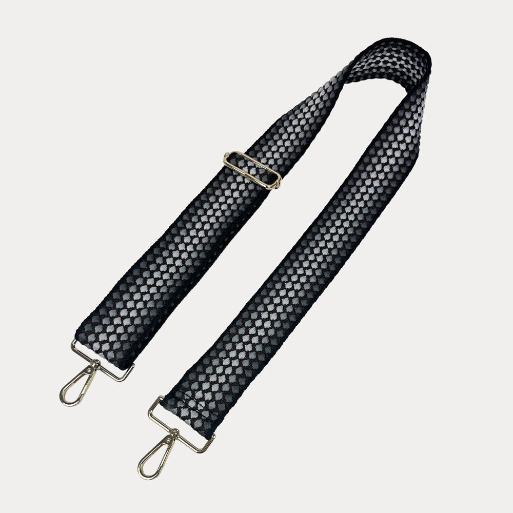Black patterned bag strap with metal clasps on a light gray background