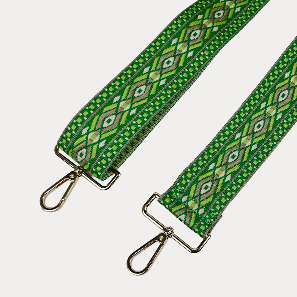 Green, light green, tan, diamond patterned bag strap with gold metal clasps on a light gray background