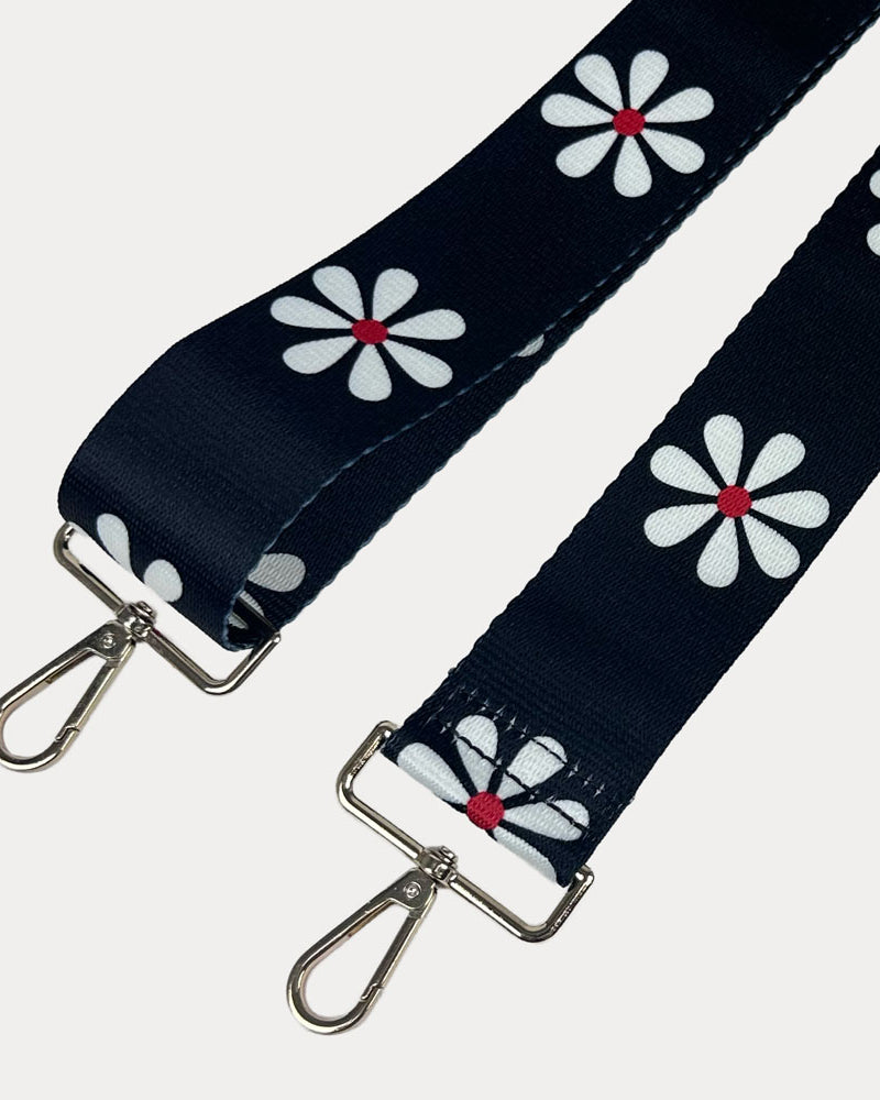 Black ground with White Flower Print bag strap with gold metal clasps on light grey background