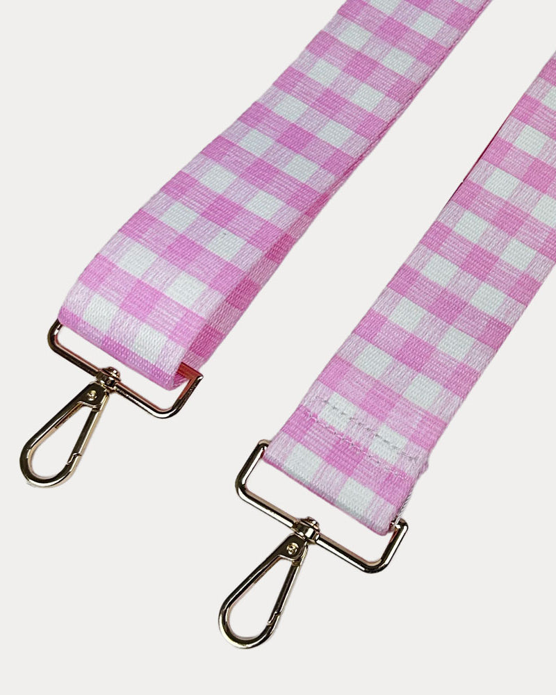 Pink and white checkered strap with gold metal clasps on a light gray background
