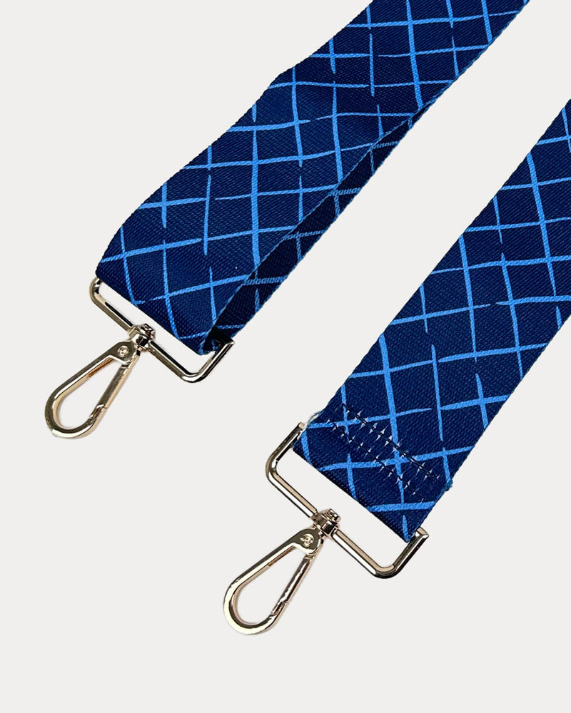 Navy and blue patterned strap with gold hardware on a white background