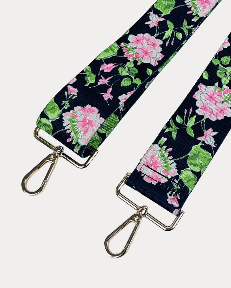 Black ground floral patterned strap with gold hardware on a light gray background