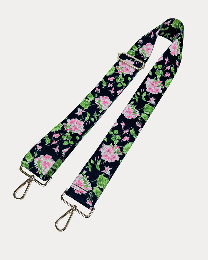 Black ground floral patterned strap with gold hardware on a light gray background