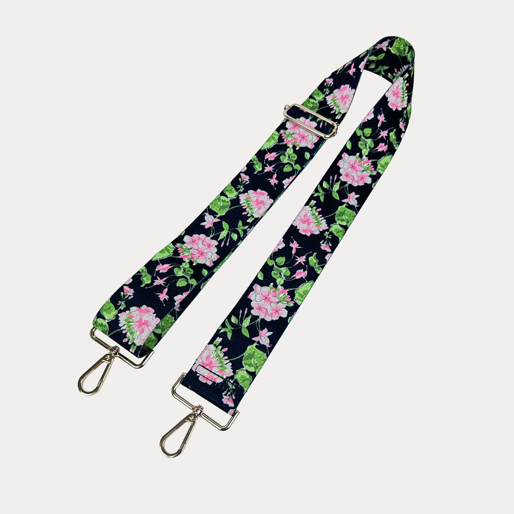 Black ground floral patterned strap with gold hardware on a light gray background