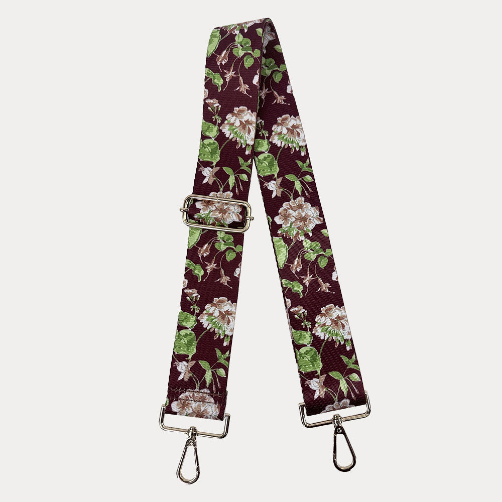 Burgundy ground floral patterned strap with gold hardware on a light gray background