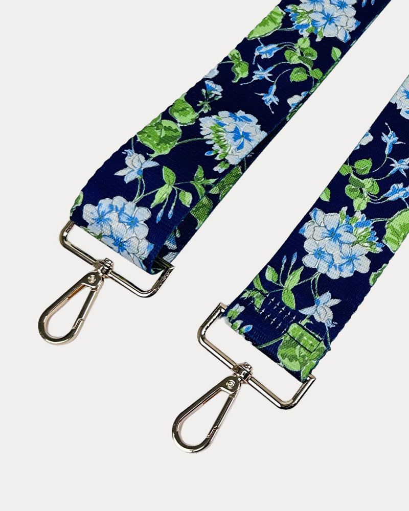 Navy ground floral patterned strap with gold hardware on a light gray background