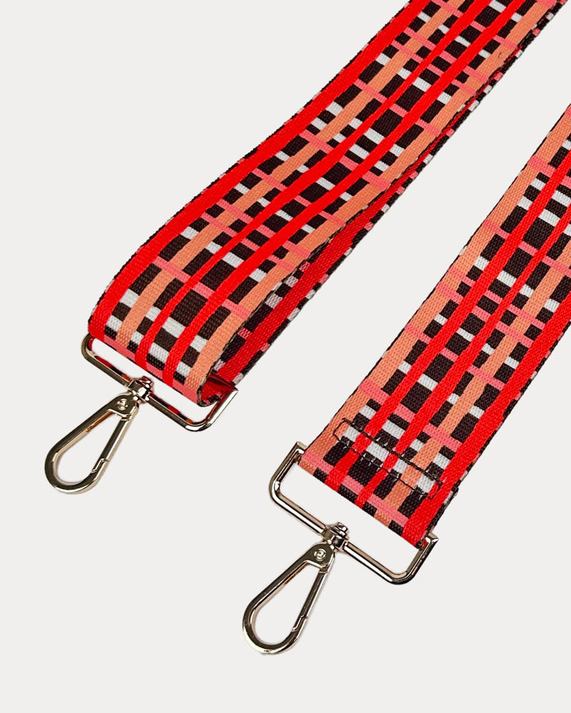 Brown, red and peach plaid strap with gold metal hardware on a white background