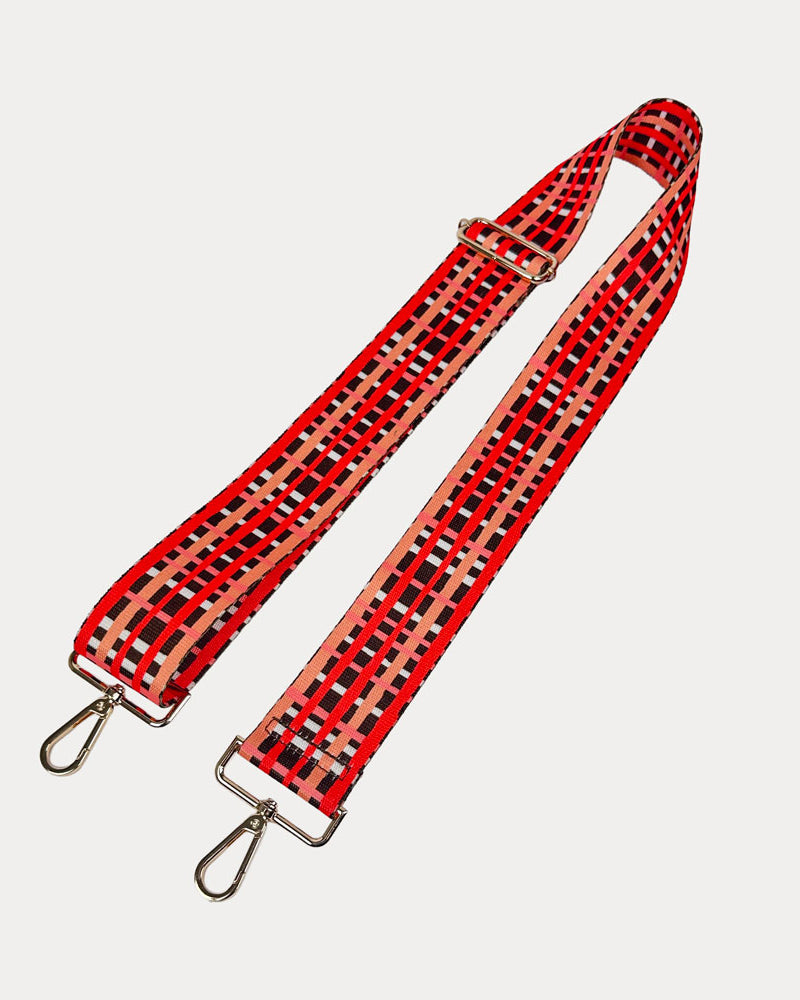 Brown, red and peach plaid strap with gold metal hardware on a white background