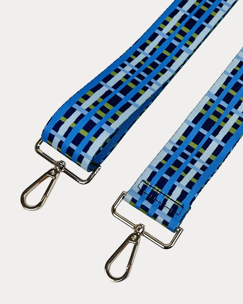Navy, blue and green plaid strap with gold metal hardware on a white background