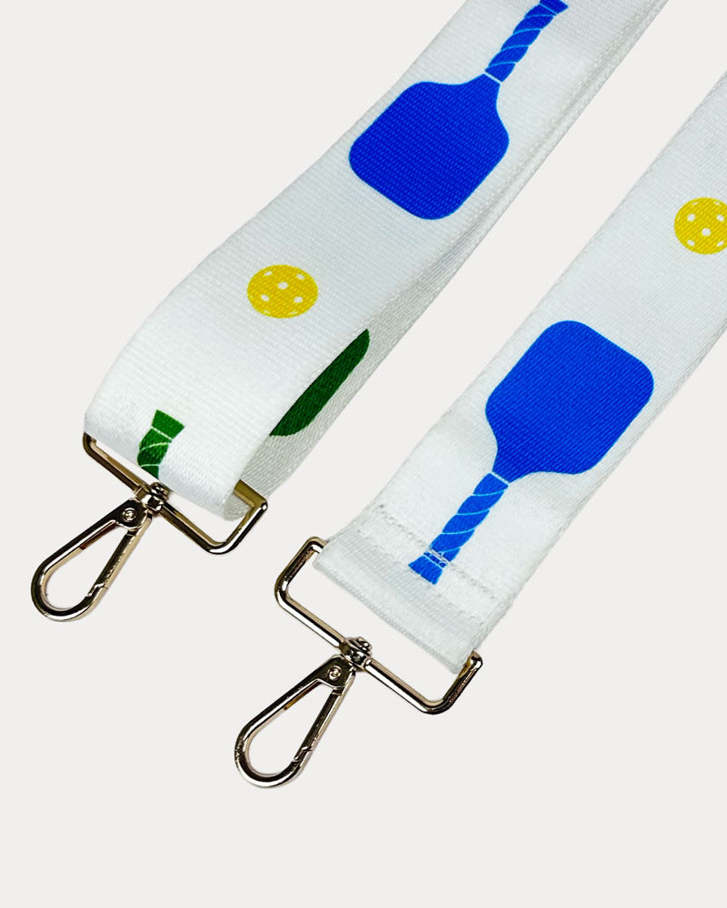 White ground with colorful pickleball paddles and white pickleball graphics with gold hardware bag strap