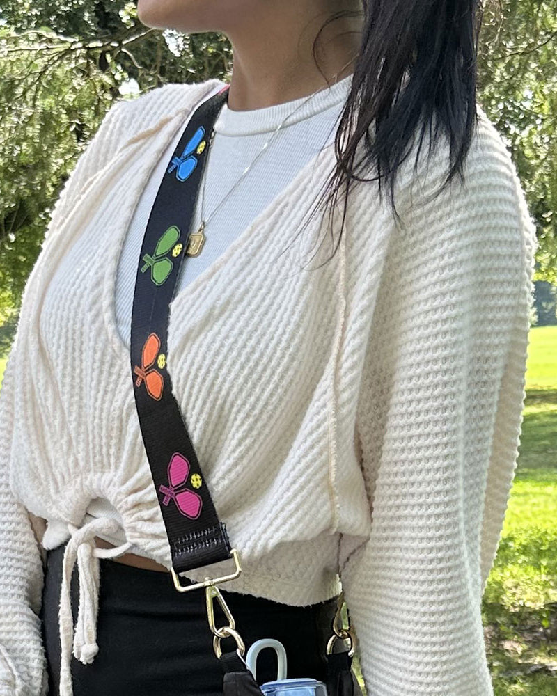 woman wearing black ground multi colored pickleball pattern bag strap
