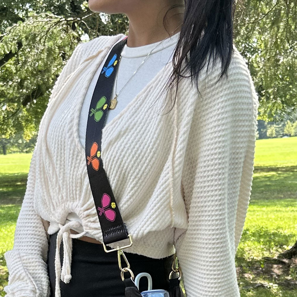 woman wearing black ground multi colored pickleball pattern bag strap