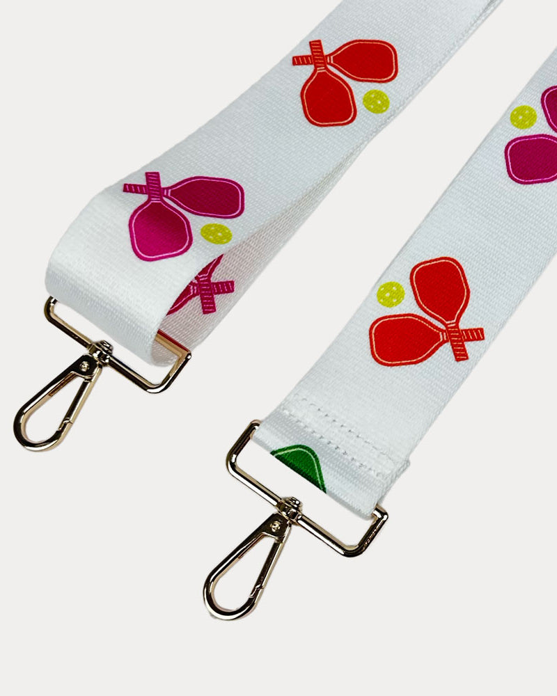 White ground with colorful pickleball paddle graphics with gold hardware bag strap
