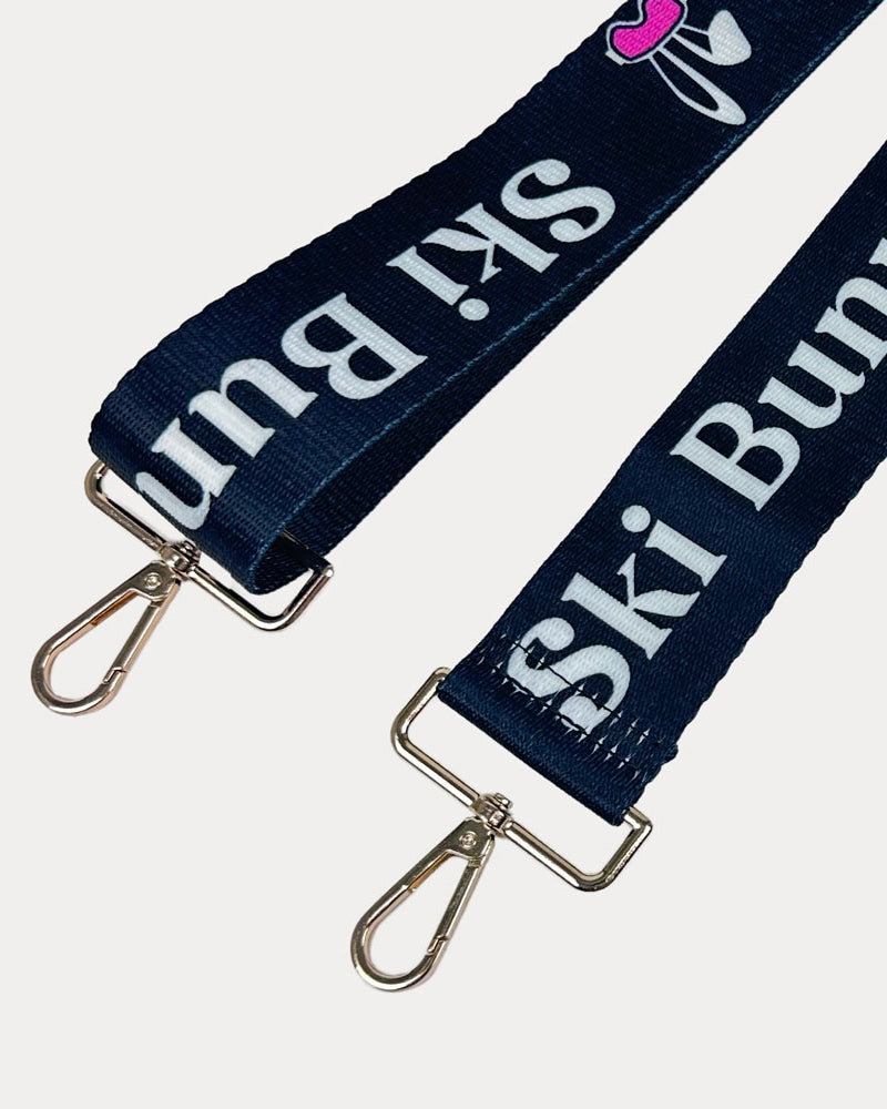 Black ground with Ski Bunny text in White and white bunny with pink accents printed bag strap with gold hardware