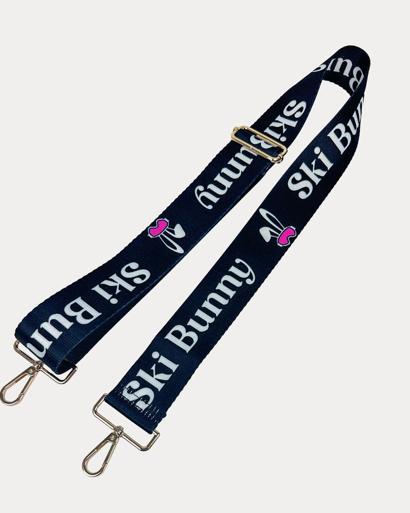 Black ground with Ski Bunny text in White and white bunny with pink accents printed bag strap with gold hardware