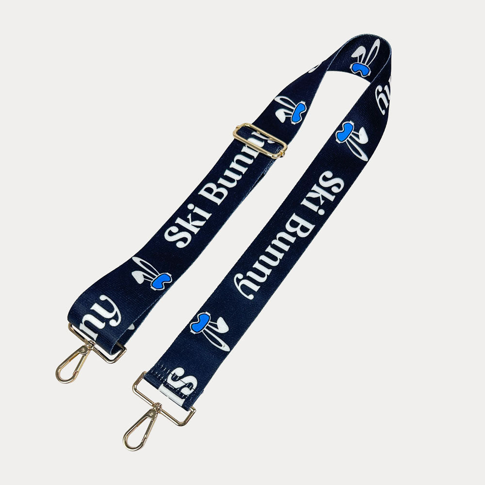 Black ground with Ski Bunny text in White and white bunny with blue accents printed bag strap with gold hardware