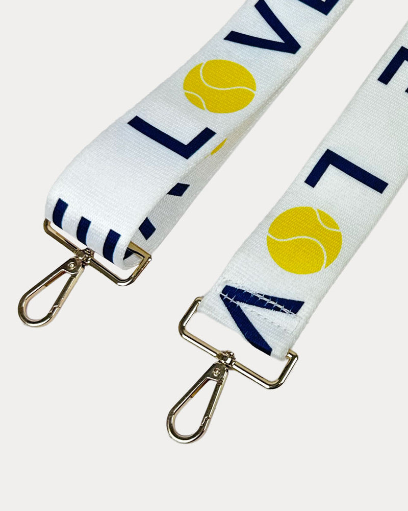 White ground with 'LOVE' text and tennis ball graphics with gold hardware bag strap