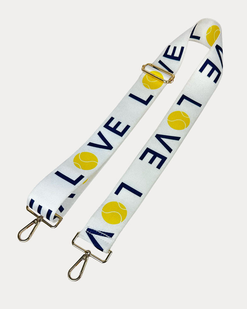 White ground with 'LOVE' text and tennis ball graphics with gold hardware bag strap