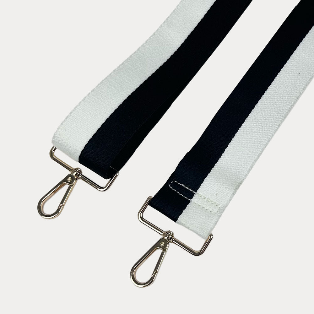 Black and White striped bag strap with gold hardware on a light gray background
