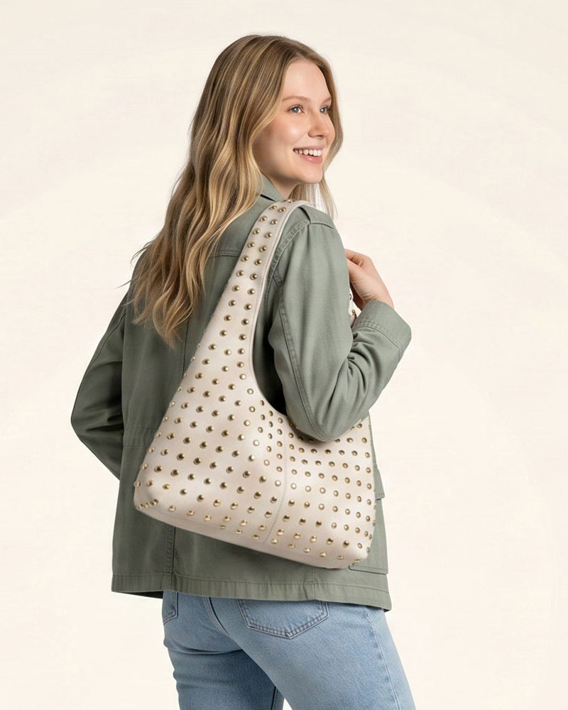 Woman wearing a cream suede hobo with gold studs
