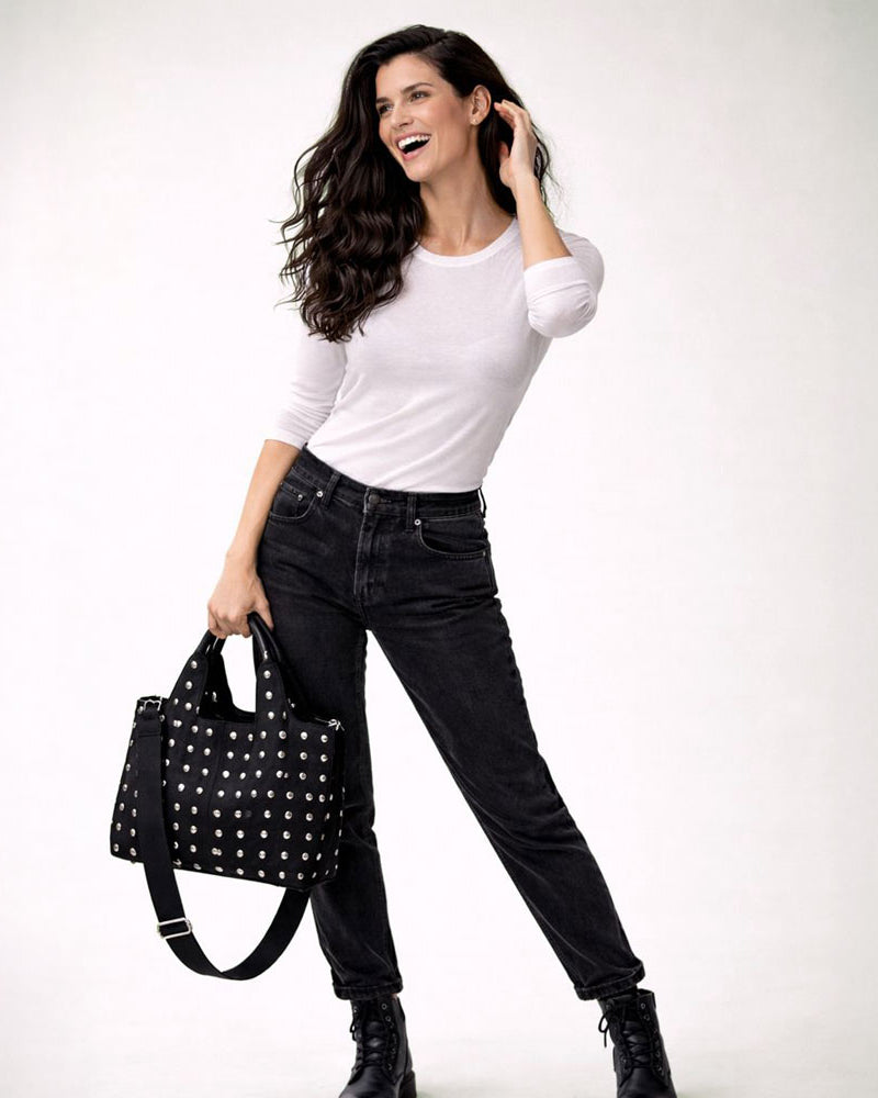 Woman holding a black studded tote against a white background