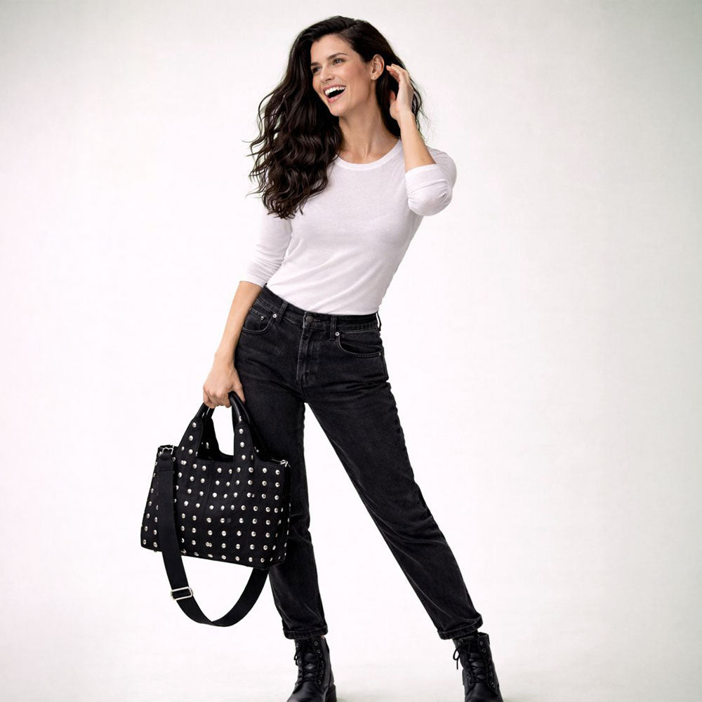 Woman holding a black studded tote against a white background