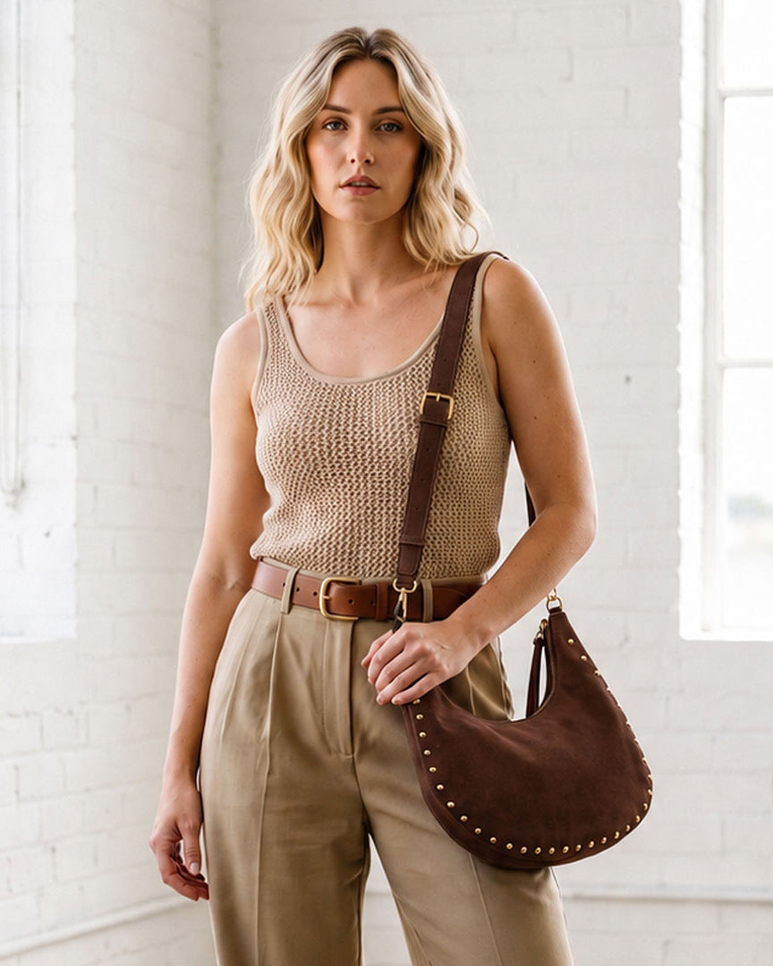Woman in a loft space wearing a chocolate vegan suede bag with studs