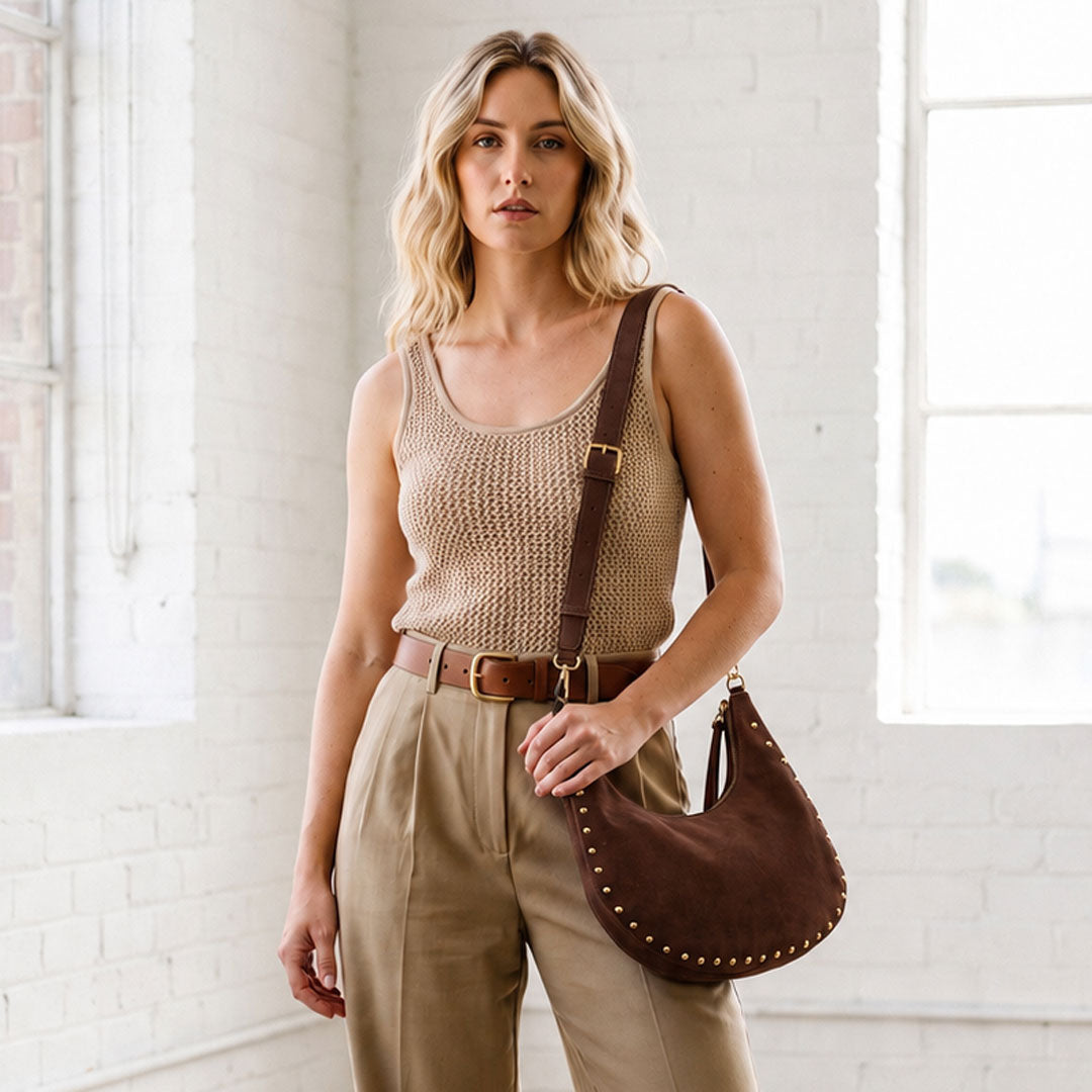 Woman in a loft space wearing a chocolate vegan suede bag with studs