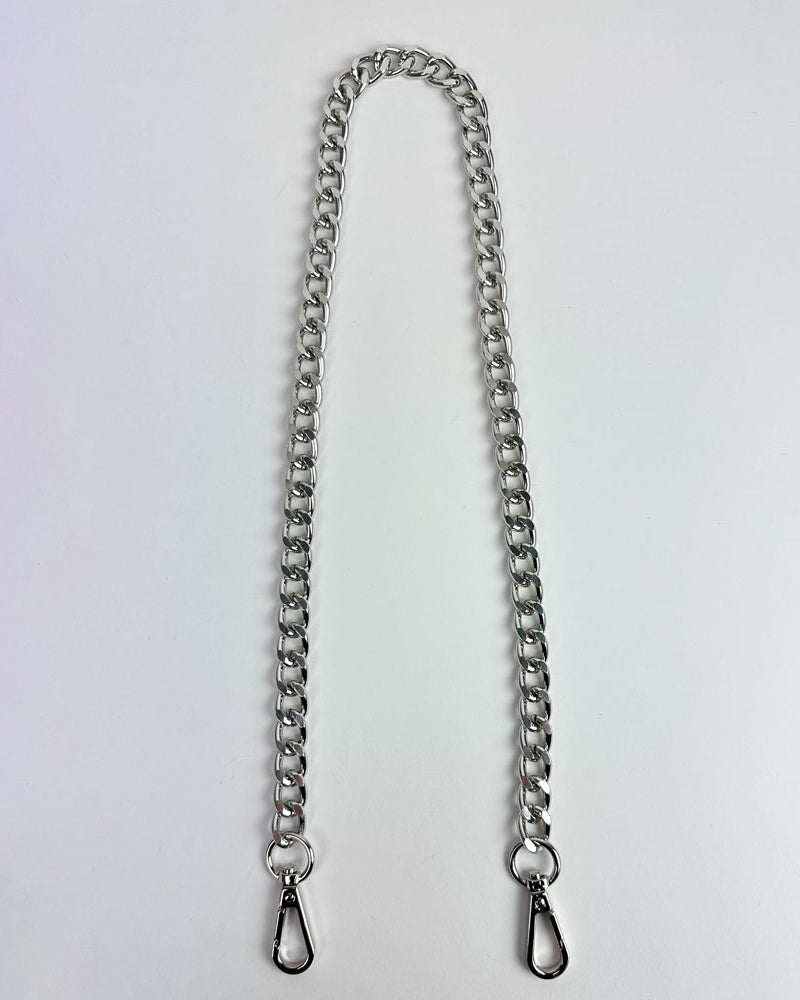 Silver metal chain bag strap on a light grey background