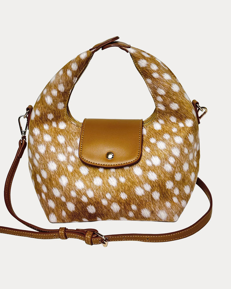 Handbag with deer print and camel vegan leather accents and camel vegan leather bag strap on a light gray background