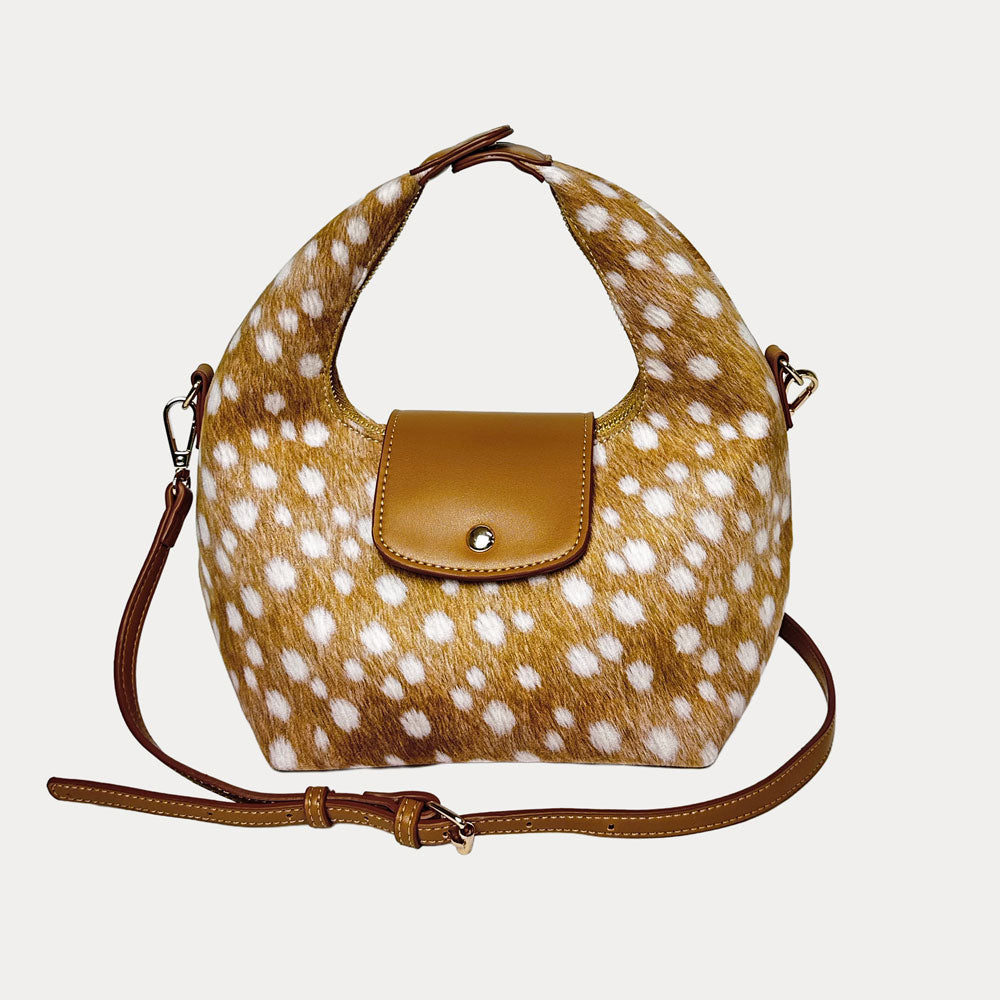 Handbag with deer print and camel vegan leather accents and camel vegan leather bag strap on a light gray background