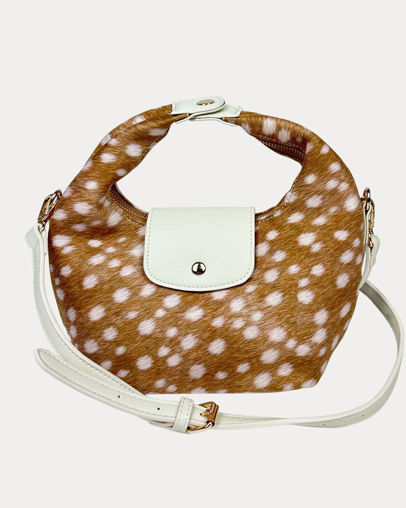 Handbag with deer print and cream vegan leather accents and a cream vegan leather bag strap on a light gray background