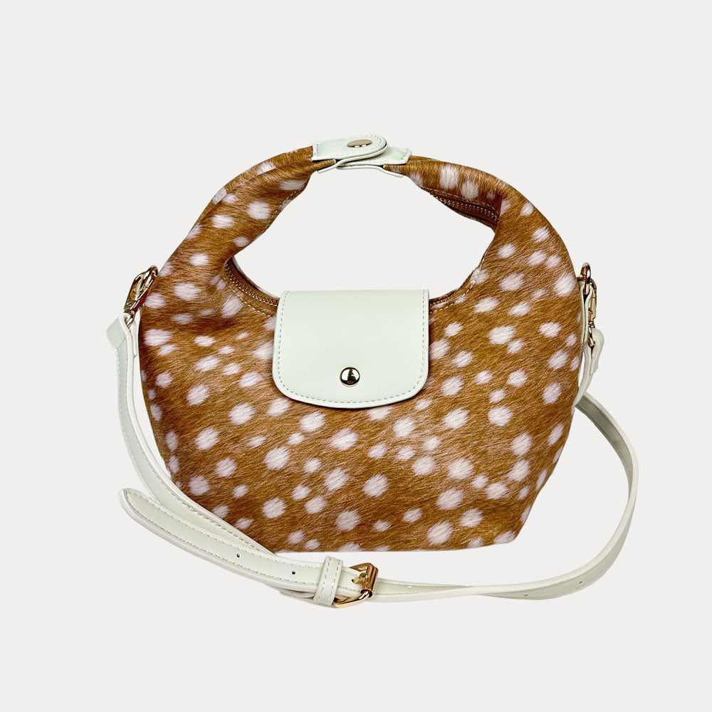 Handbag with deer print and cream vegan leather accents and a cream vegan leather bag strap on a light gray background