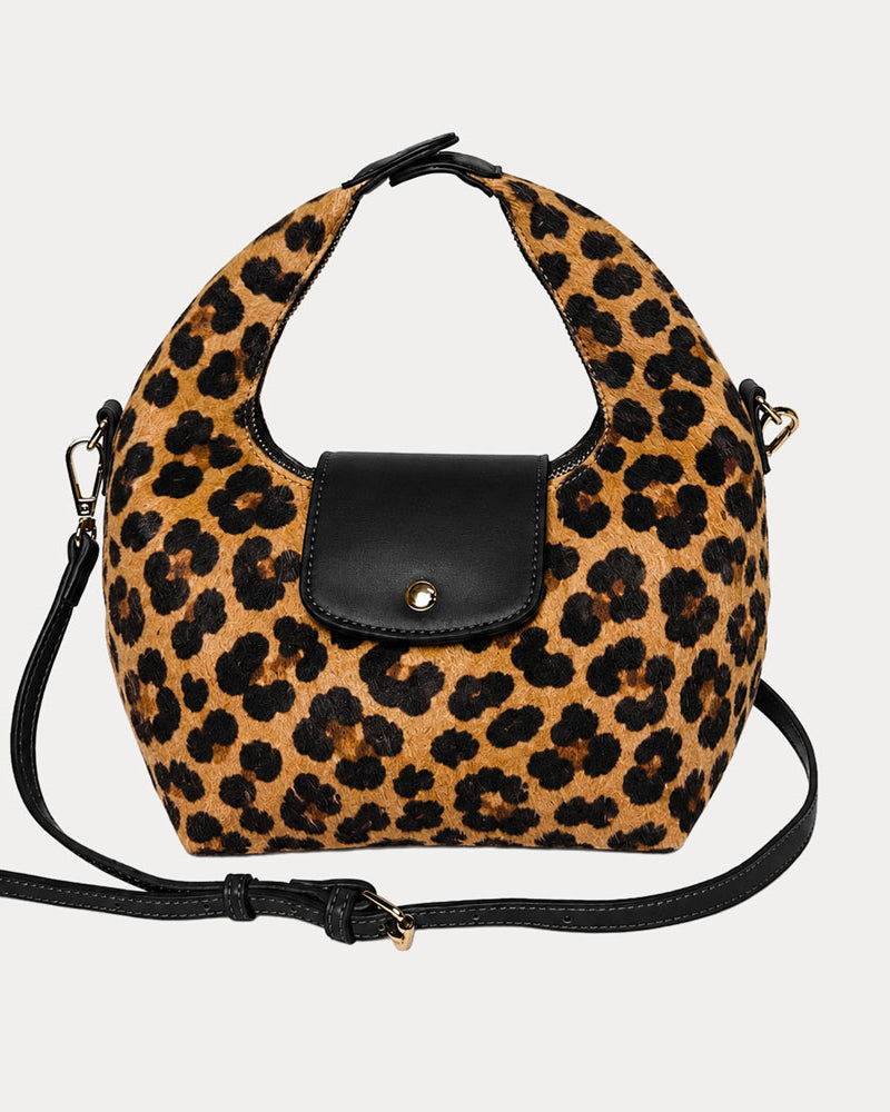 Handbag with leopard print vegan suede and black leather accents on a light gray background