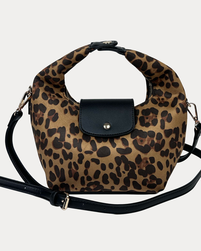Handbag with leopard print and black vegan leather accents and a black vegan leather bag strap on a light gray background