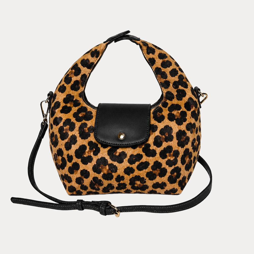Handbag with leopard print vegan suede and black leather accents on a light gray background