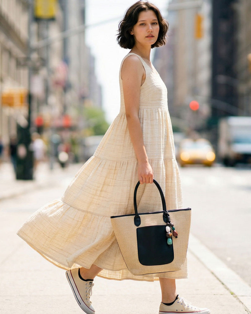 Woman in a cream maxi dress, carrying a Raffia Tote.