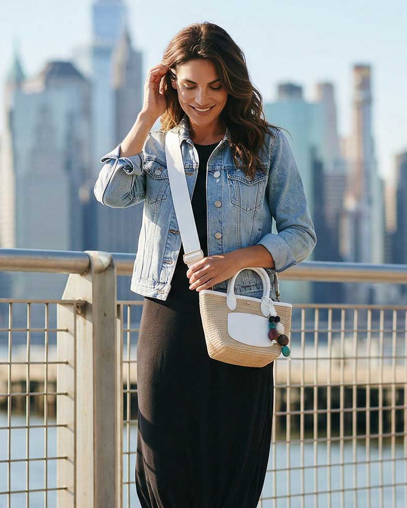 Woman holding a raffia handbag with a city skyline in the background