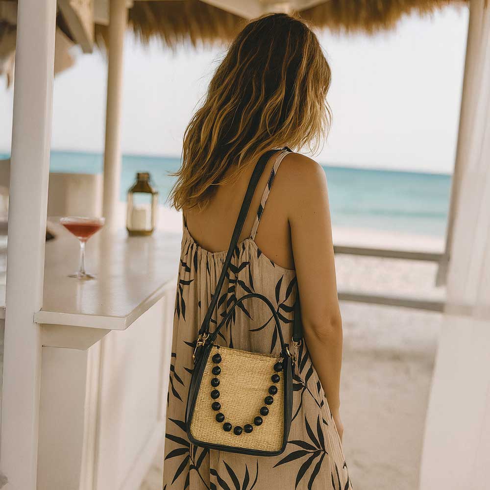 Woman in a floral dress with a raffia bag by a beach bar