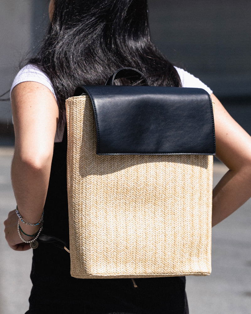 woman wearing the chelsea raffia backpack in black