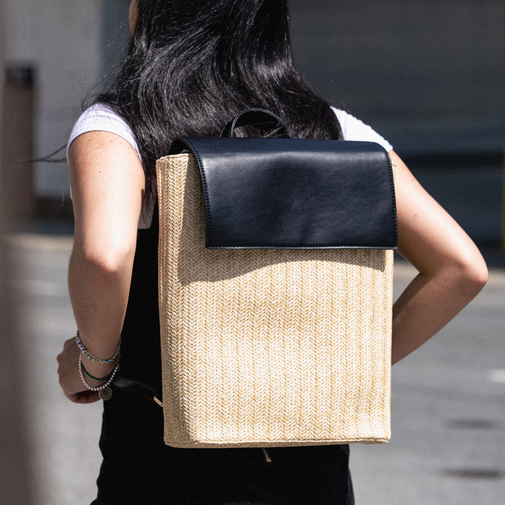 woman wearing the chelsea raffia backpack in black
