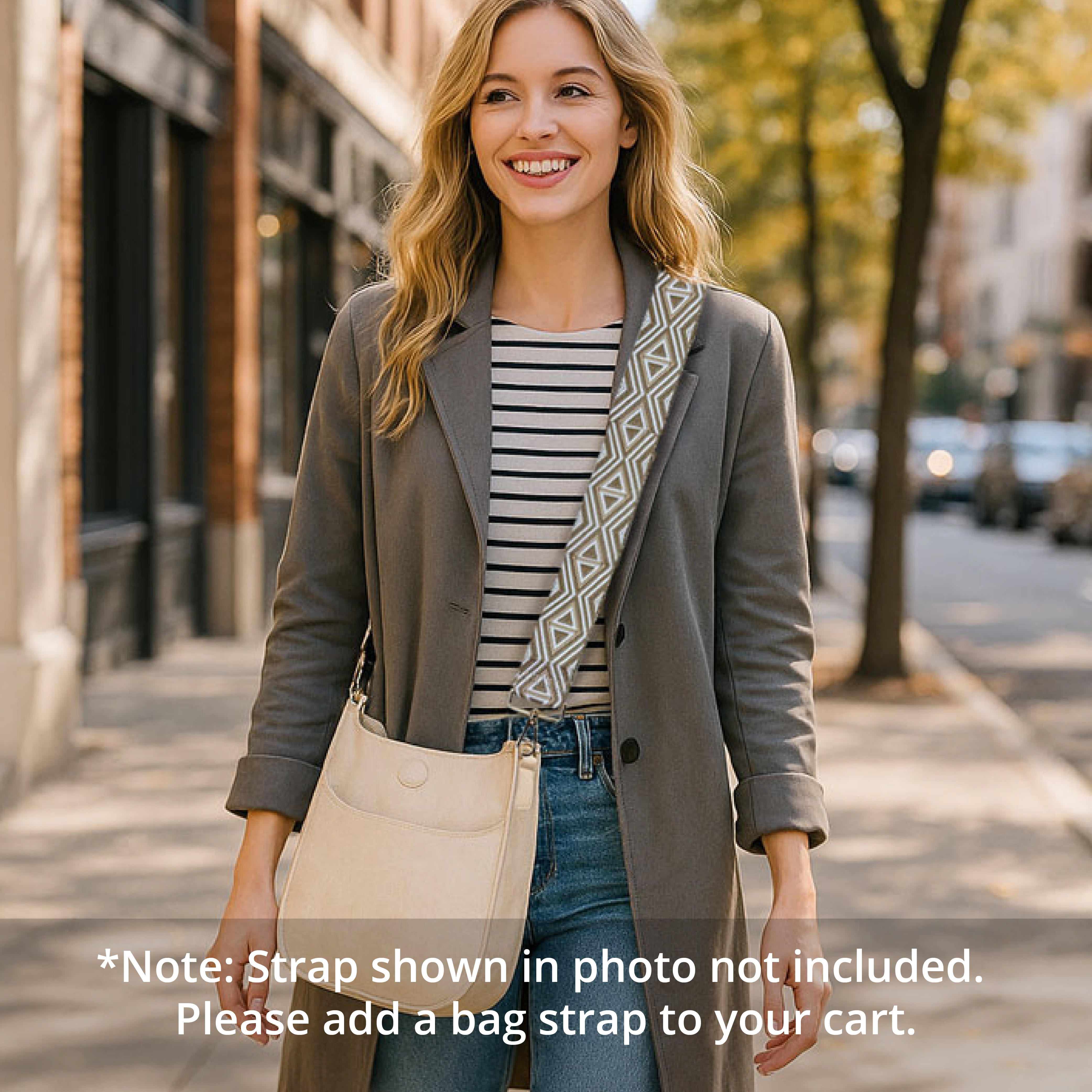 Woman walking on a city street wearing a gray coat with a cream messenger bag with a bag strap over her shoulder.