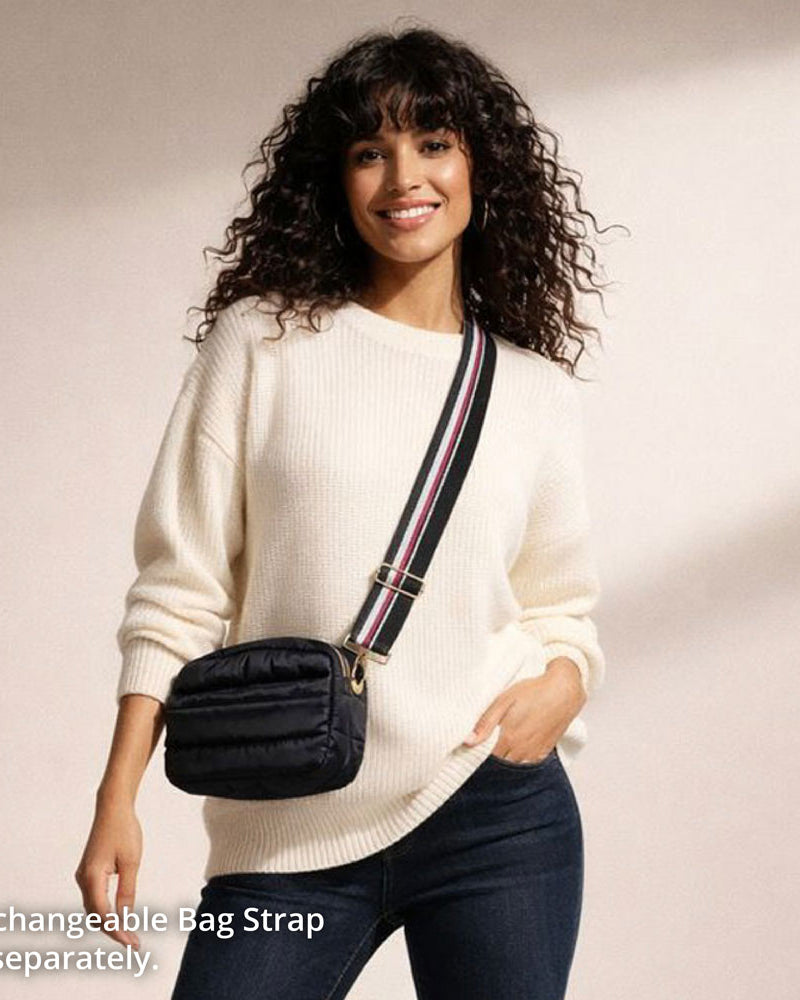Woman wearing a white sweater with a black bag featuring an interchangeable strap.